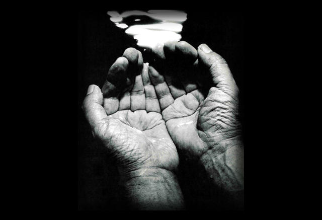 1970年代、当時の長崎社長が「飲める水」に浄化された高月事業所の水を手で汲み上げている様子