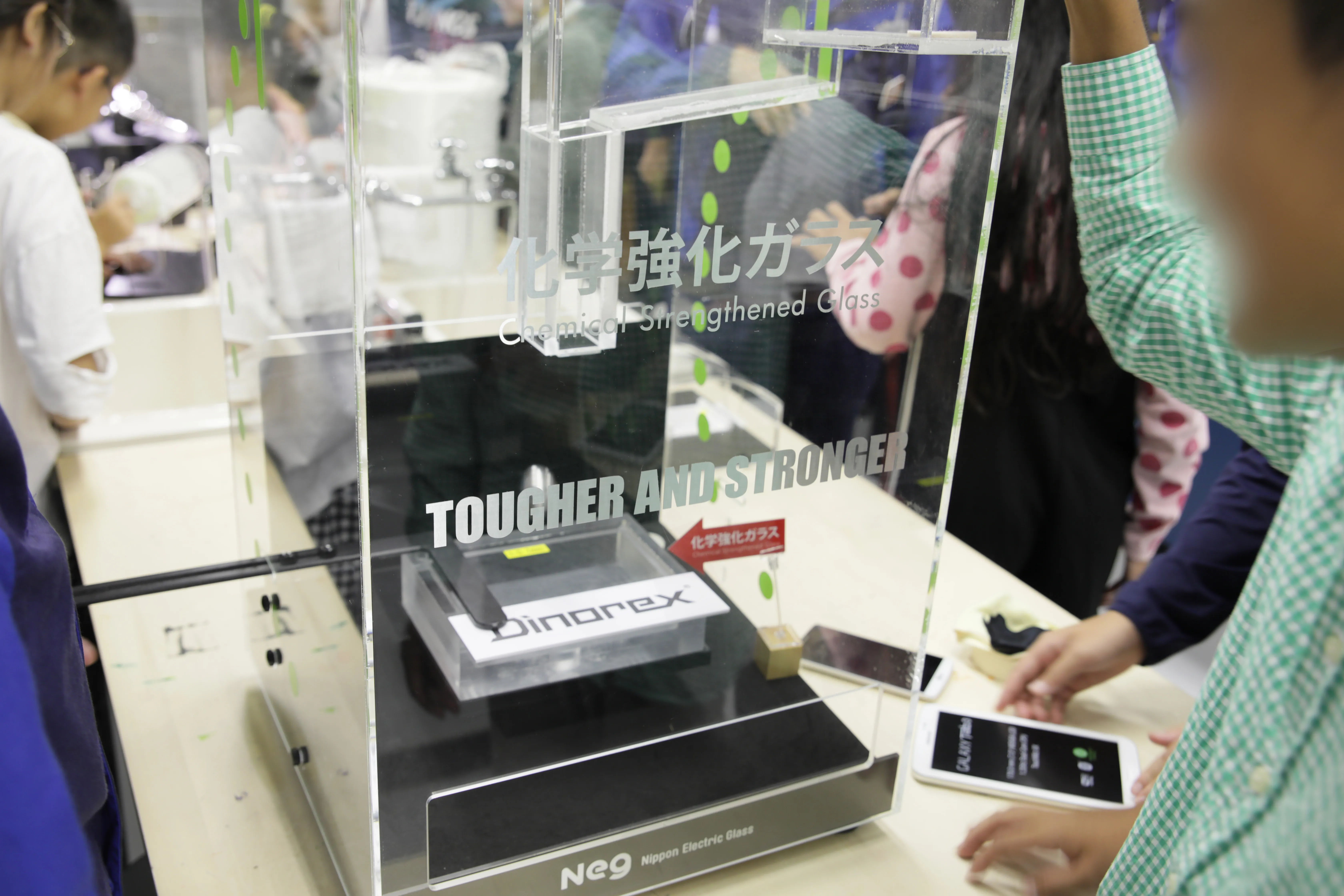 装置を使って、化学強化ガラスに鉄球を落とす実験をする子どもたち