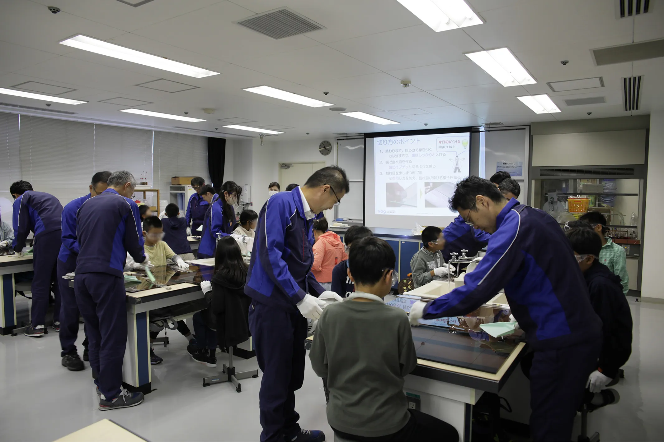 ガラスカット体験をする子どもたちとそれを手伝うNEG社員